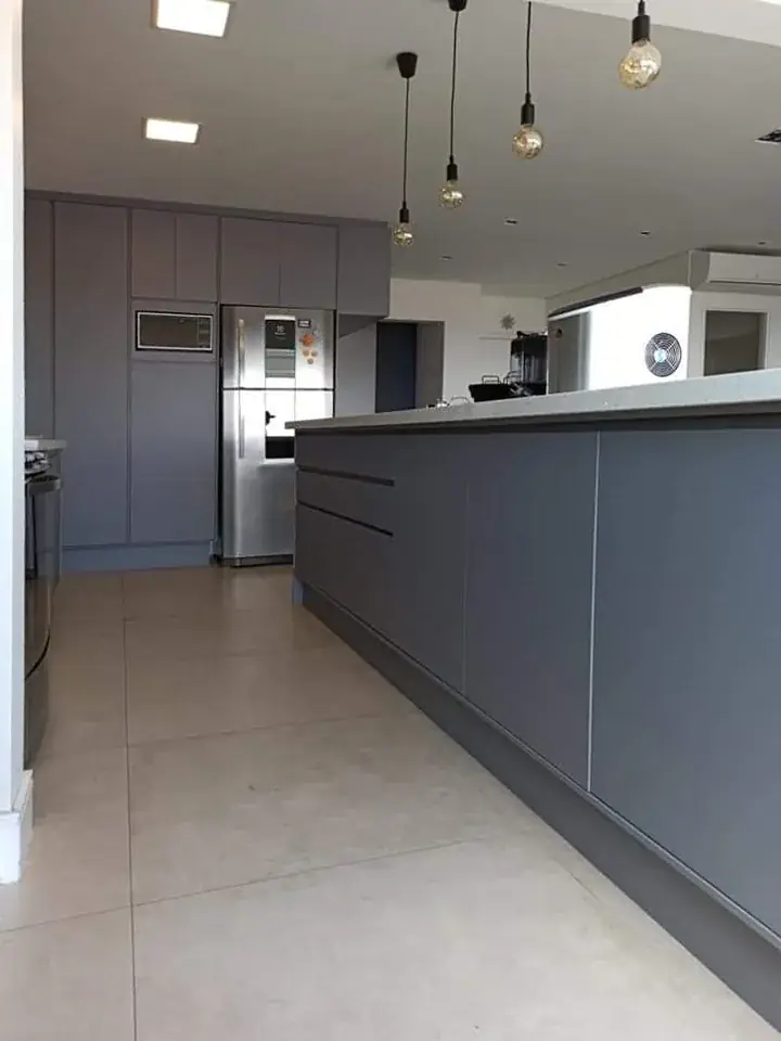 Cozinha em lacado mate cinza com ilha central e coluna de eletrodomésticos integrada