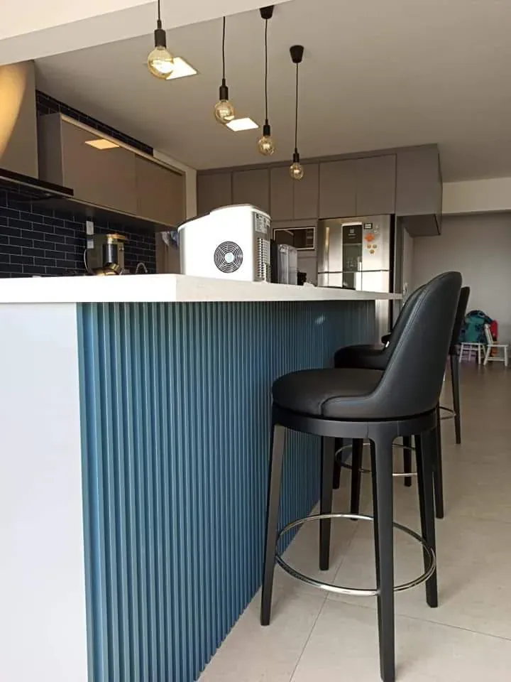 Ilha de cozinha com frente ripada, bancada clara e candeeiros suspensos, produzida pelo Atelier da Madeira